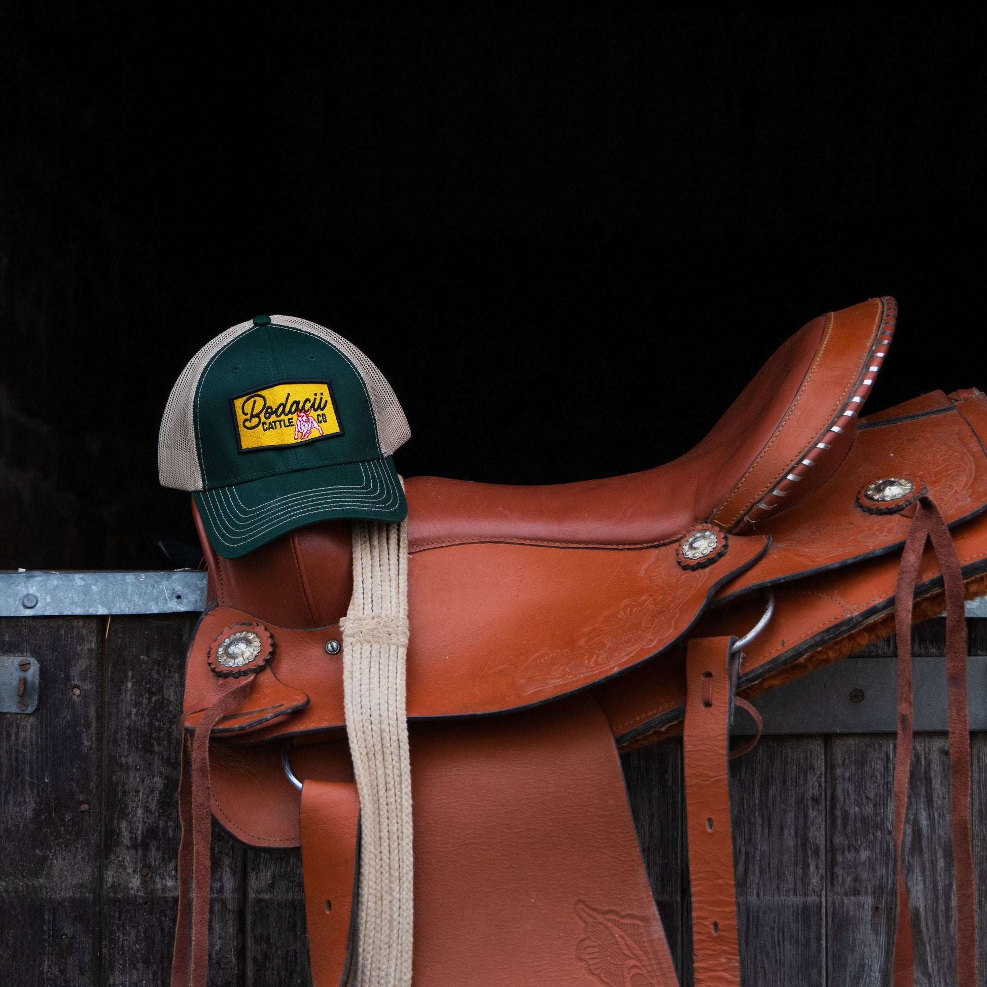 Brown western saddle with a green and beige trucker cowboy cap 