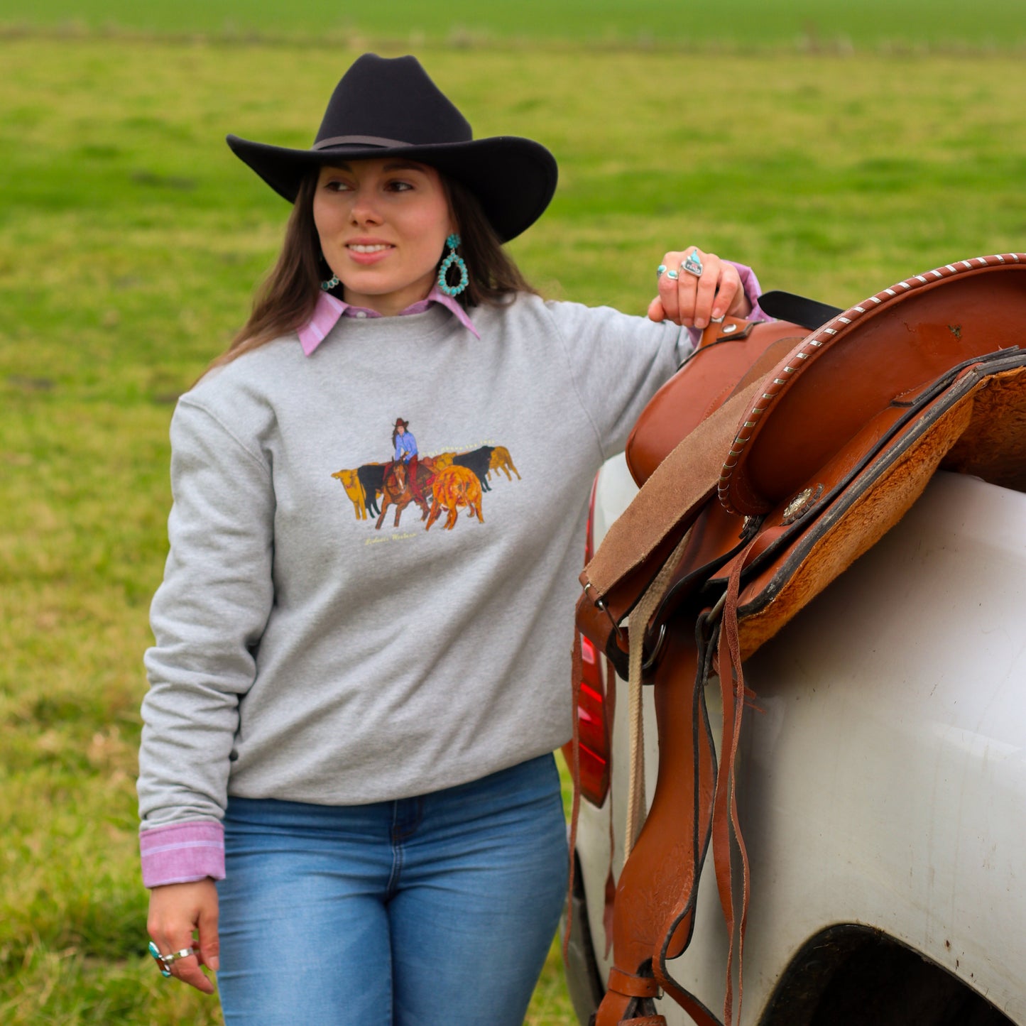 cowgirl in field wearing cattle cutting sweatshirt