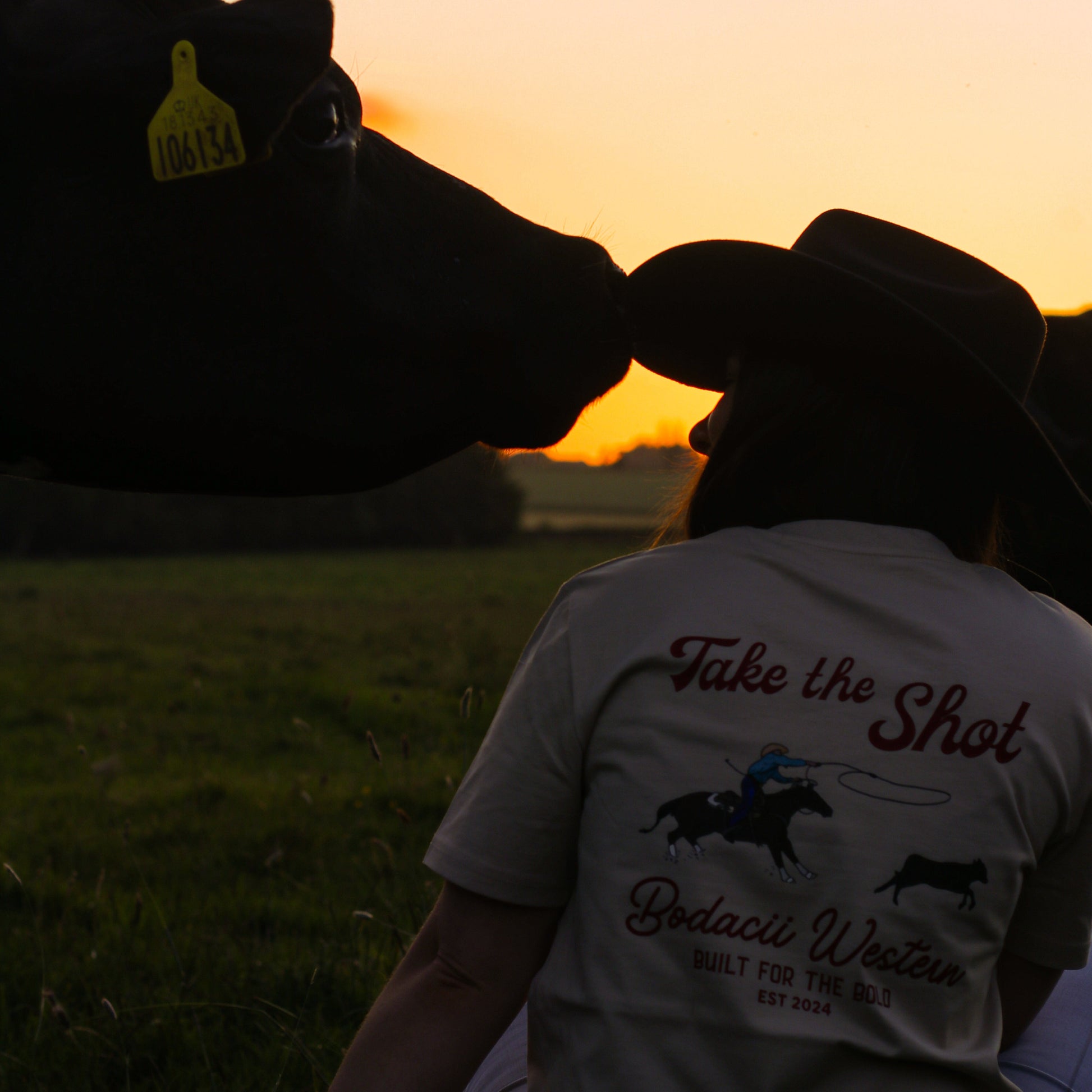 cowgirl wearing roping western tshirt with cattle and sunset